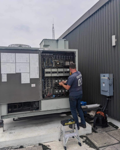 Commercial HVAC technician servicing a rooftop unit in summer in Chatham-Kent.